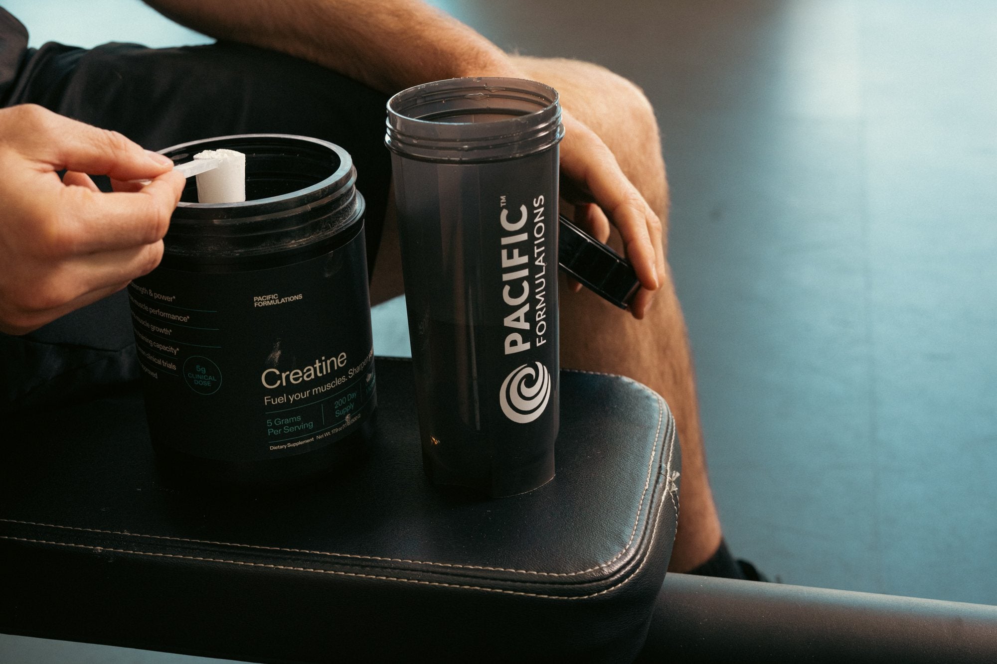 Scooping Pacific Formulations creatine beside a Pacific shaker bottle